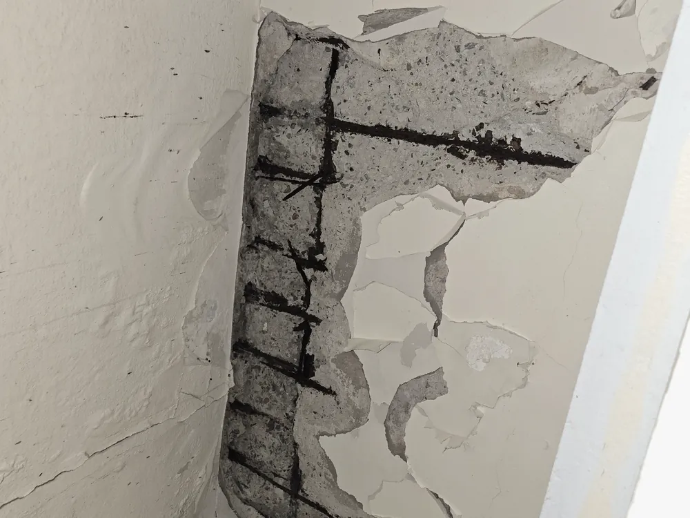Corroded reinforcing bars and closely spaced transverse reinforcement exposed where concrete has broken away at a corner, in a Puerto Rico building