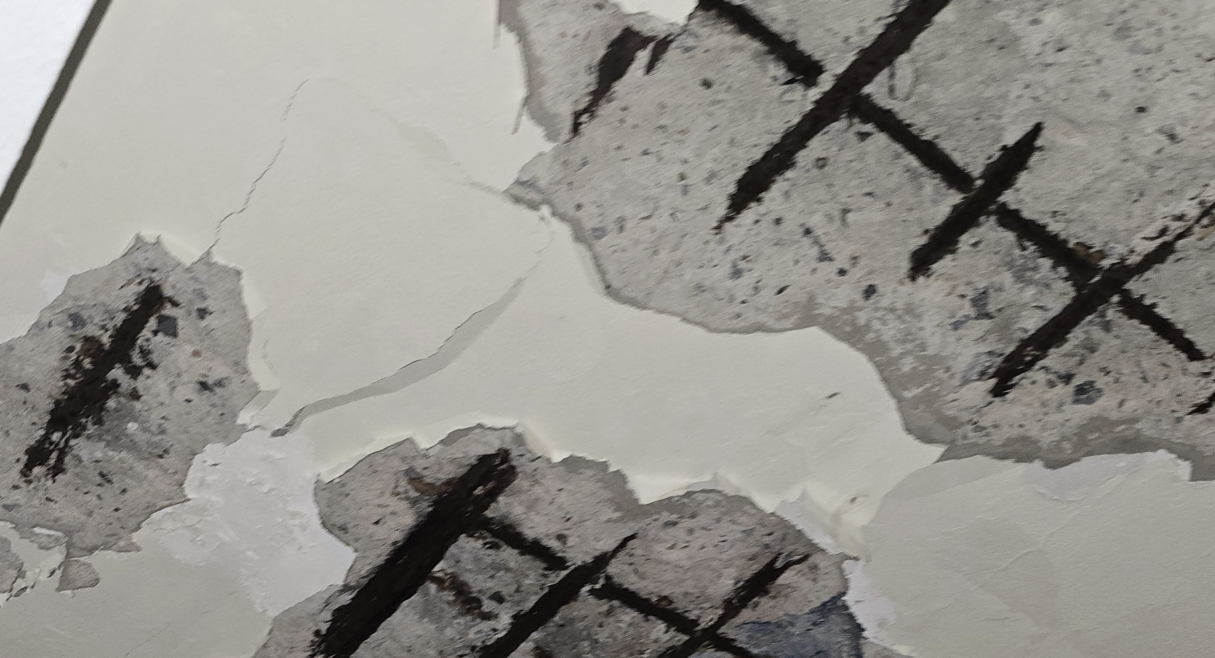 Corroded reinforcing-steel grid exposed where the painted finish and the cementitious cover beneath it have spalled away